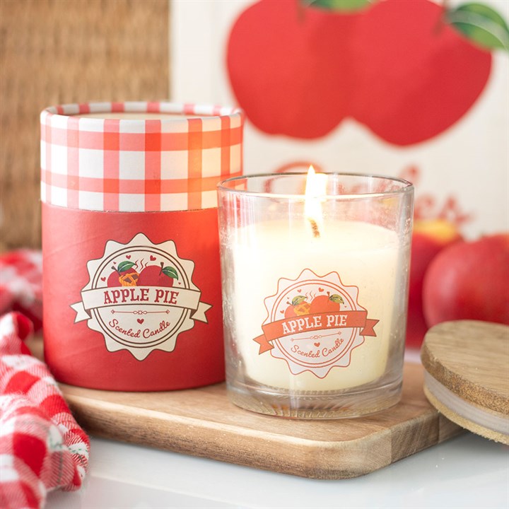 Apple pie scented candle with red checkered lid on a wooden board, apples in the background