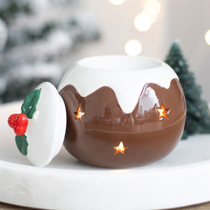 Ceramic hot chocolate mug with lid featuring a Christmas tree and holly design, set against a blurred festive background.