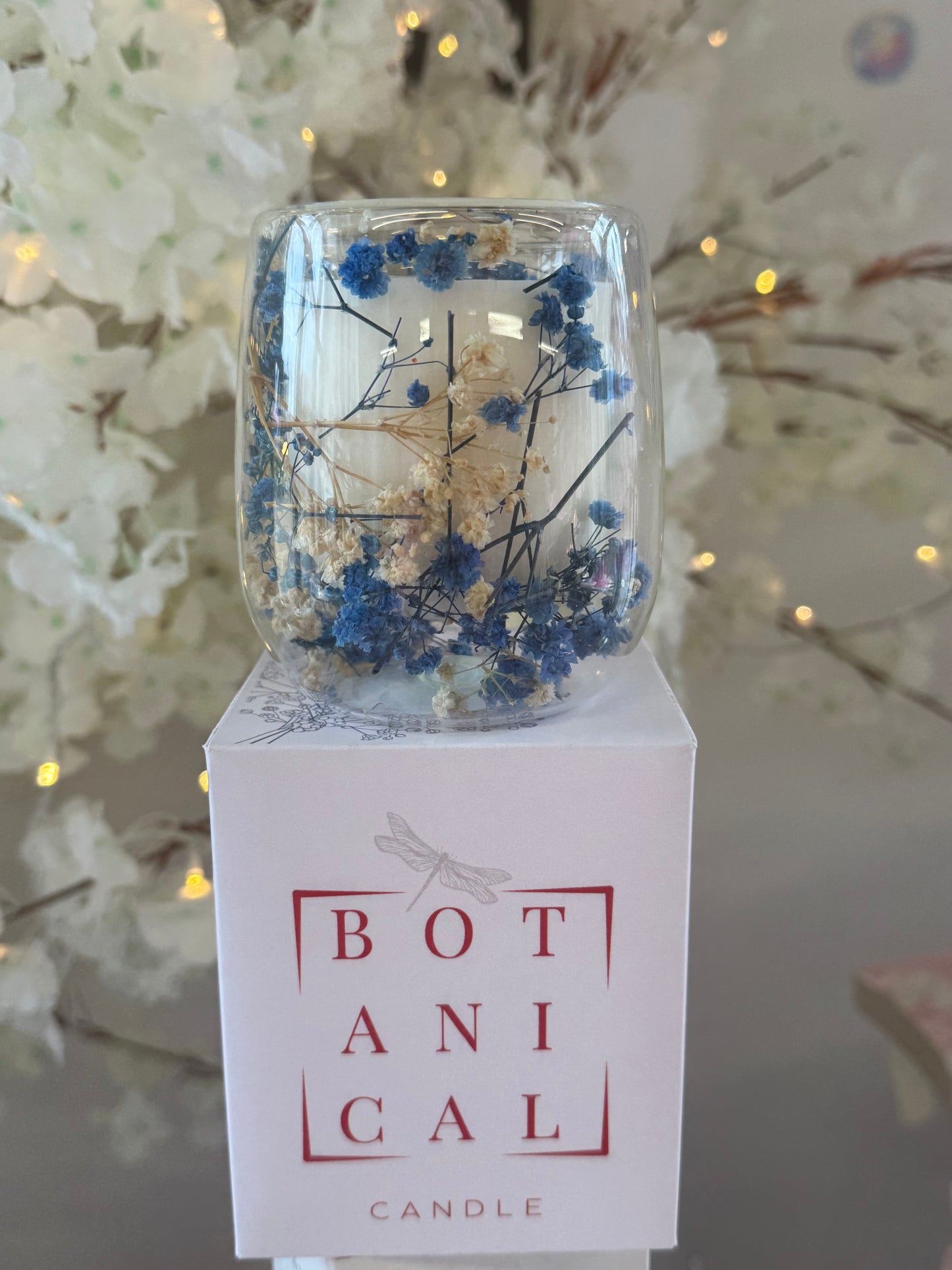 Candle with botanical design in a clear container on a white background
