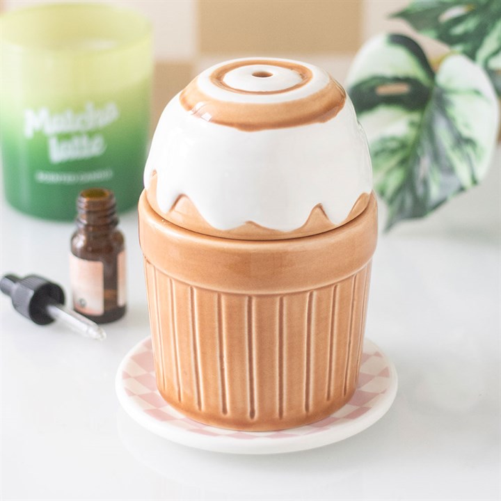 Cupcake-shaped diffuser on a white surface with a bottle and dropper in the background.