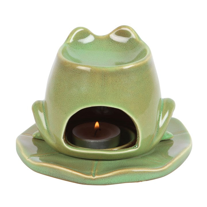 Green ceramic frog-shaped candle holder with a lit candle inside on a white background