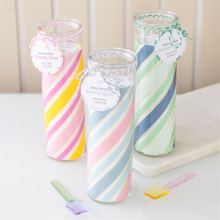 Three swirled glass candles with colorful patterns on a white surface.
