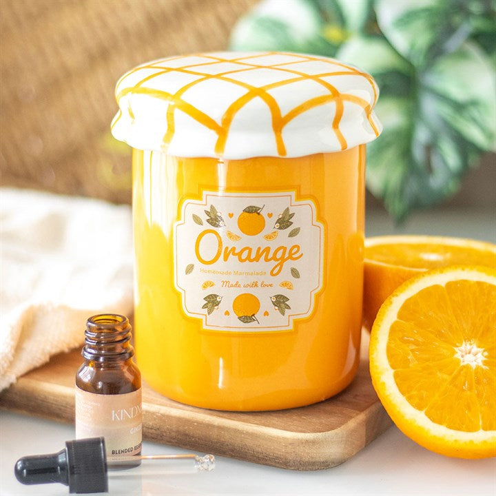 Orange-themed jar with a label, bottle, and sliced orange on a wooden board.
