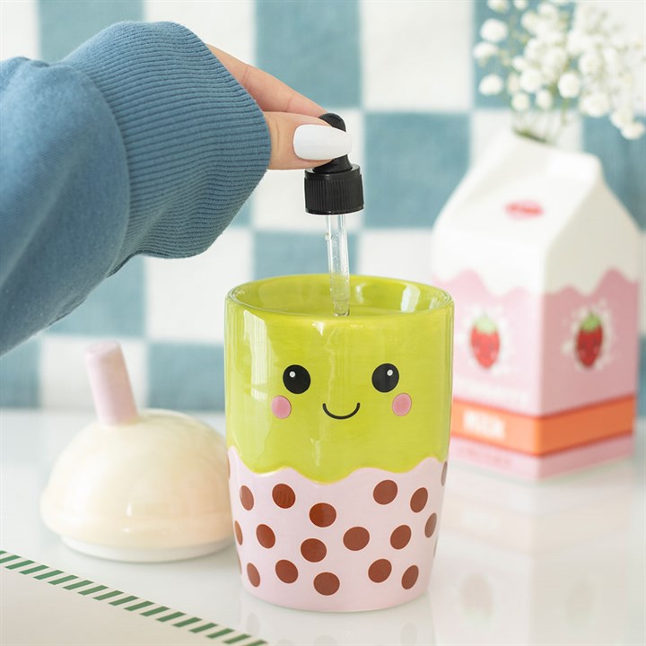 Person using a dropper to add liquid into a colorful cup with a smiley face design.