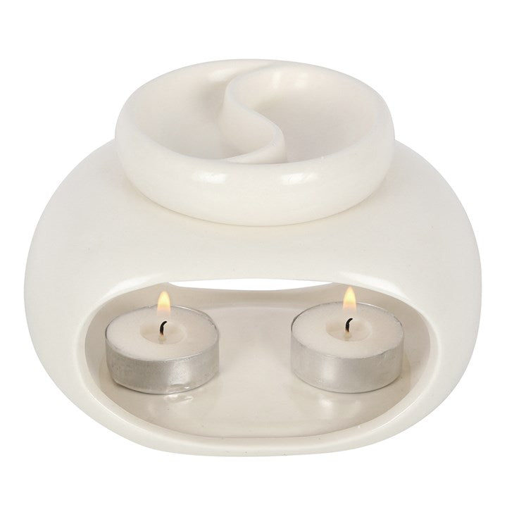 White ceramic oil burner with two lit tealights on a white background