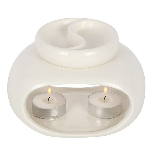 White ceramic oil burner with two lit tealights on a white background