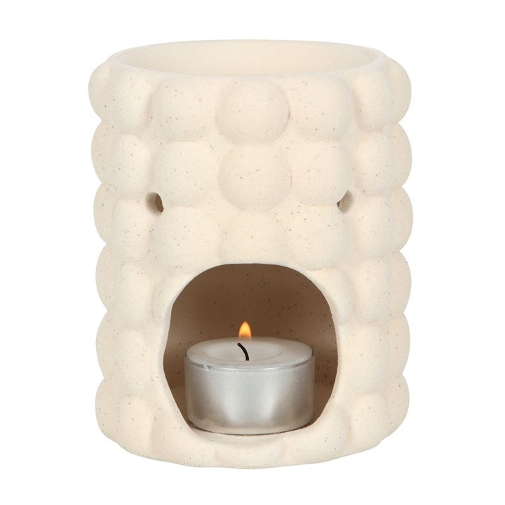 Ceramic oil burner with a lit candle inside on a white background