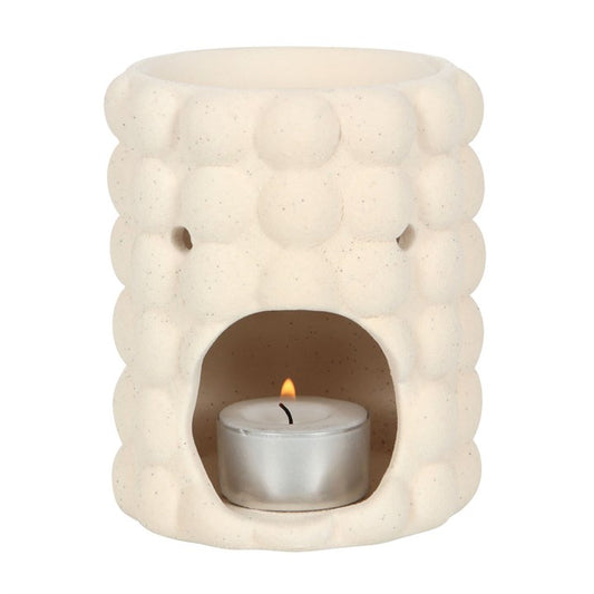 Ceramic oil burner with a lit candle inside on a white background
