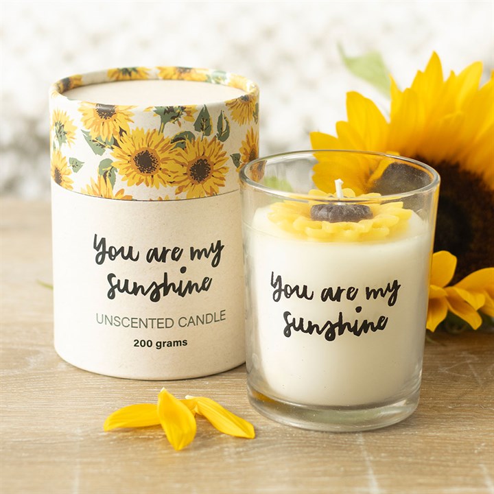 An unscented candle with white wax, featuring a 3D wax sunflower design, enclosed in a glass holder. The candle has 'You Are My Sunshine' text on it and is packaged in a matching box with sunflower print.