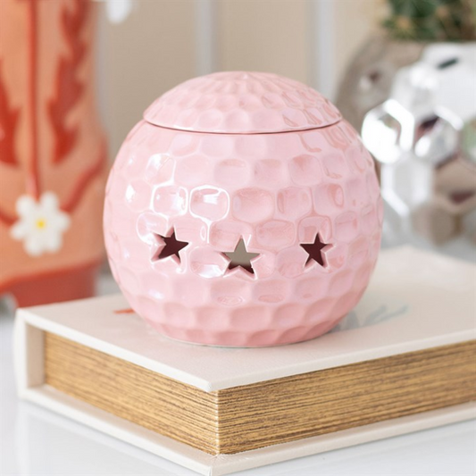 Pink textured ball-shaped container with star cutouts on a wooden surface.