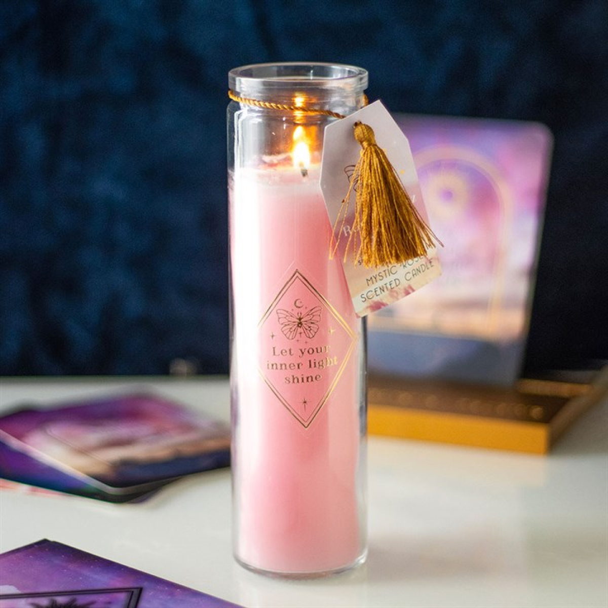 Pink candle in a glass jar with a tassel on a blurred background
