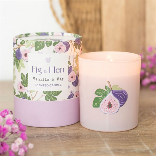 Scented candle with floral packaging labeled 'Fig & Hen Vanilla & Fig' on a wooden surface.
