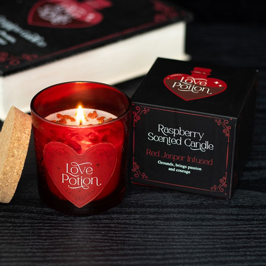 Raspberry scented candle with 'Love Potion' packaging on a dark surface