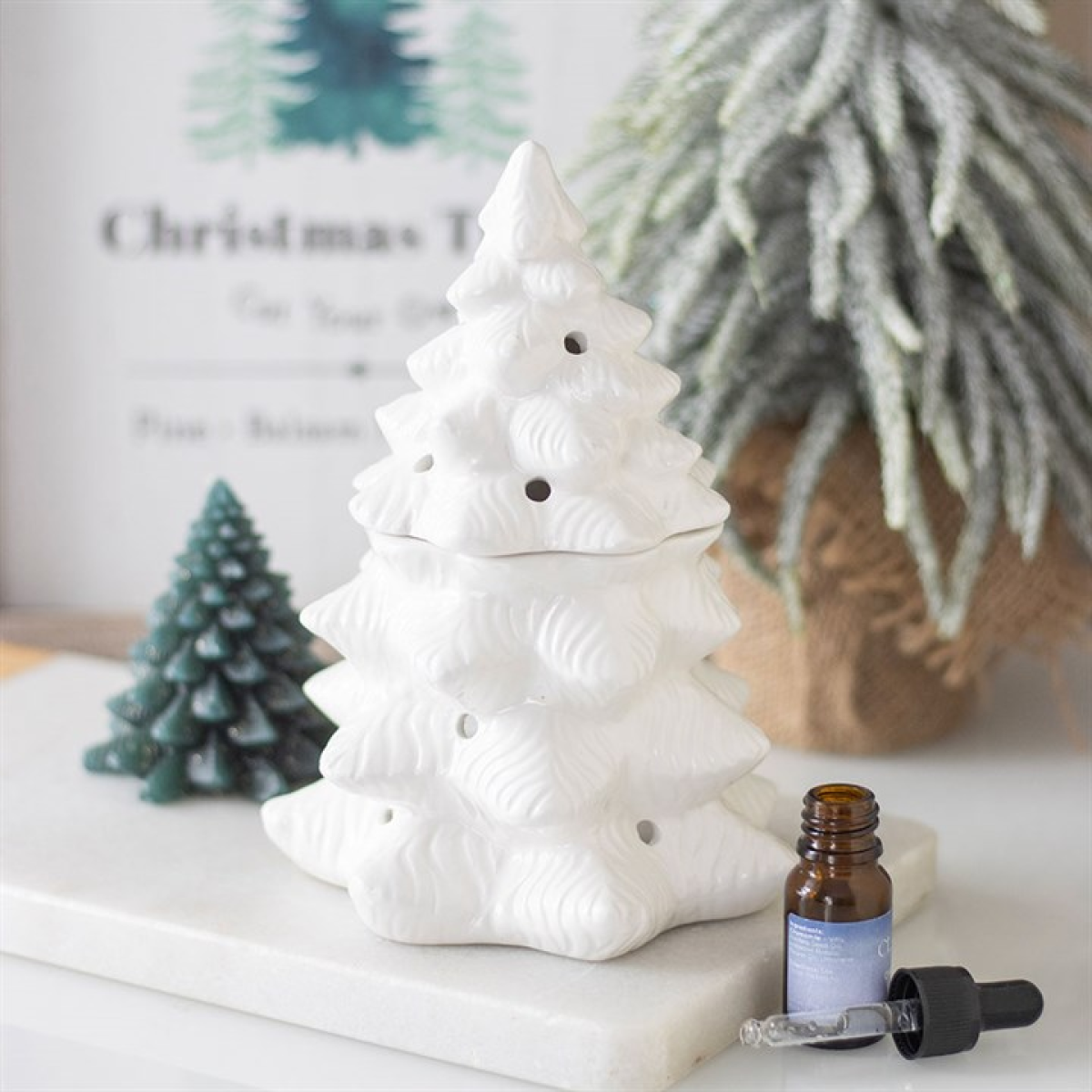 White ceramic Christmas tree with a small bottle and dropper on a light surface.