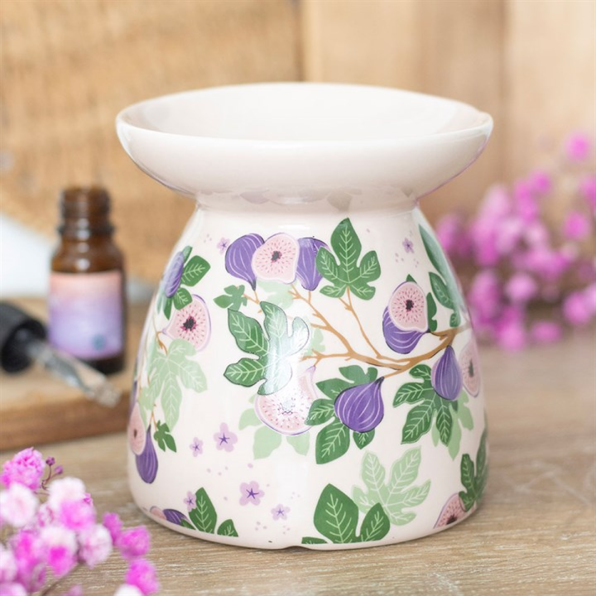 Decorative ceramic oil burner with floral design on a wooden surface.