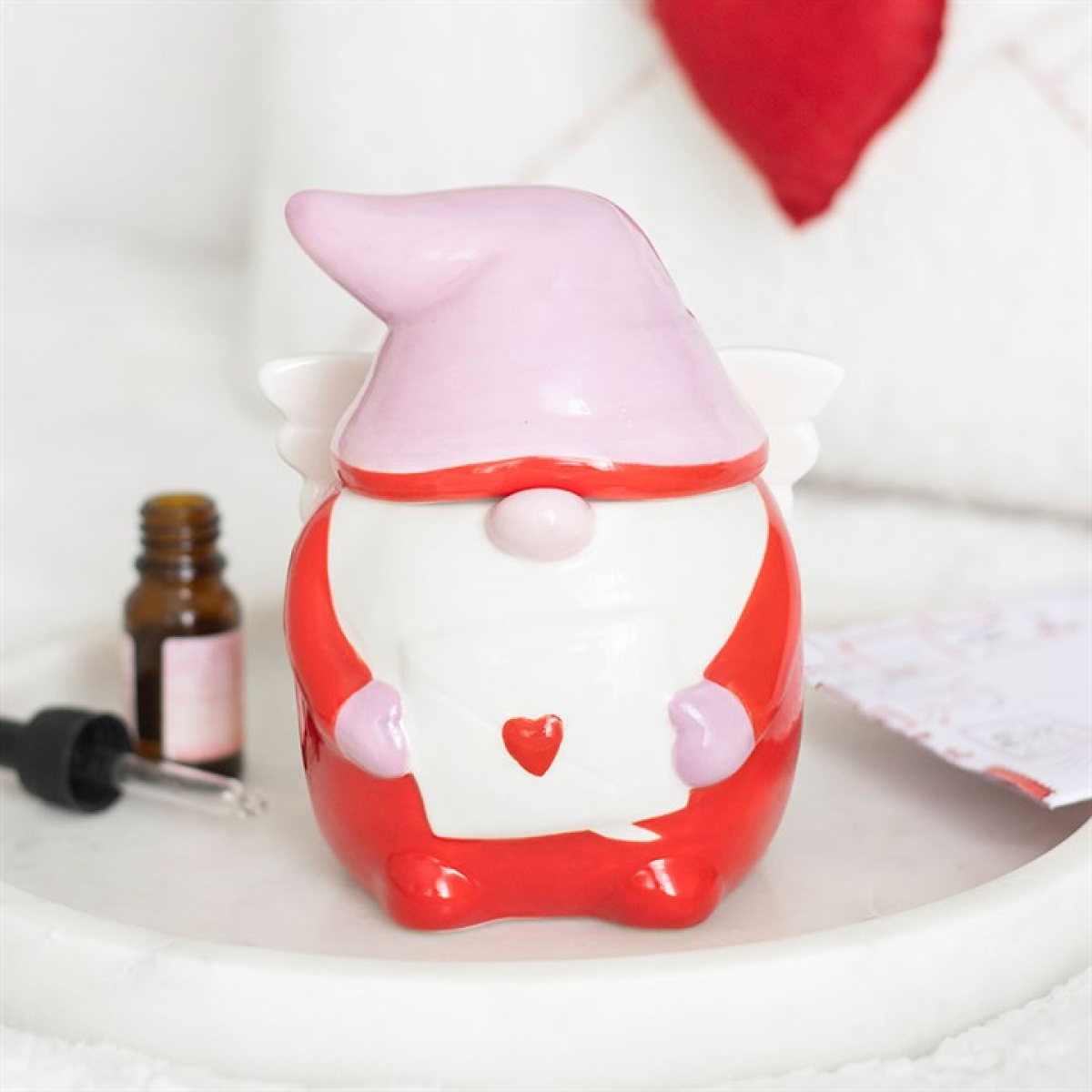 Red and white gnome figurine with a heart on a white surface