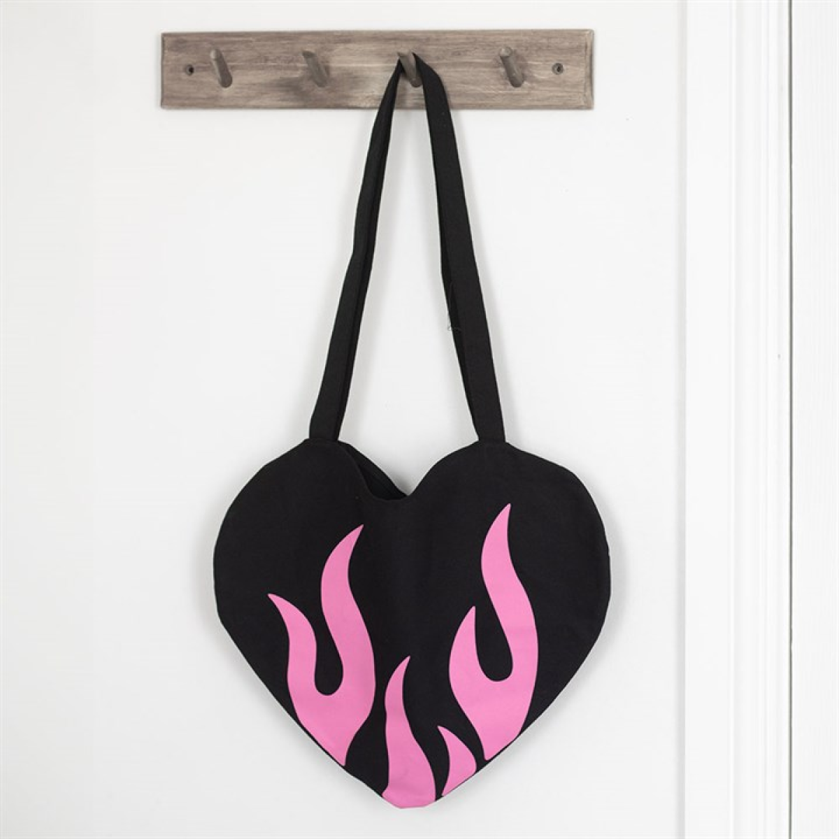 Heart-shaped bag with pink flames hanging on a wooden hook against a white background