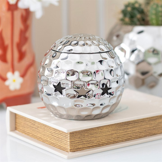Decorative silver ball with star patterns on a wooden surface