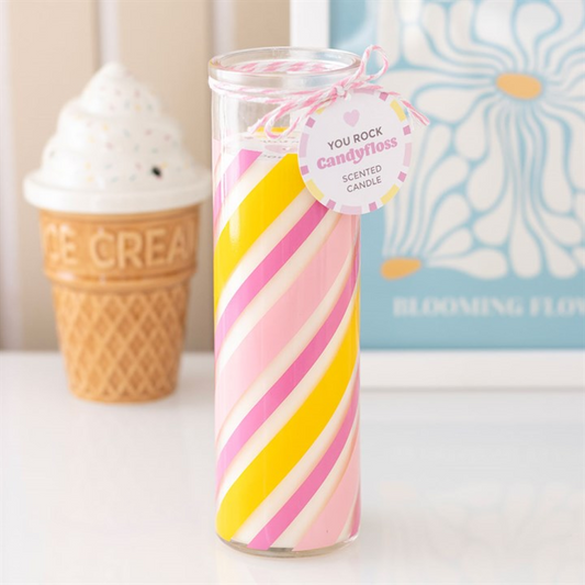 Colorful striped candle with a 'You Rock Candyfloss' tag in front of an ice cream cone and floral book.
