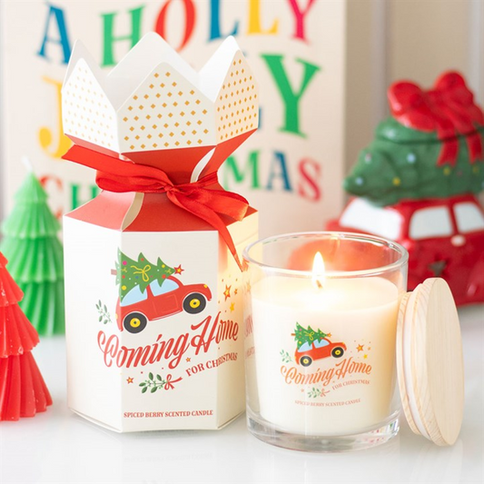Christmas-themed candle with packaging and decorative trees in the background