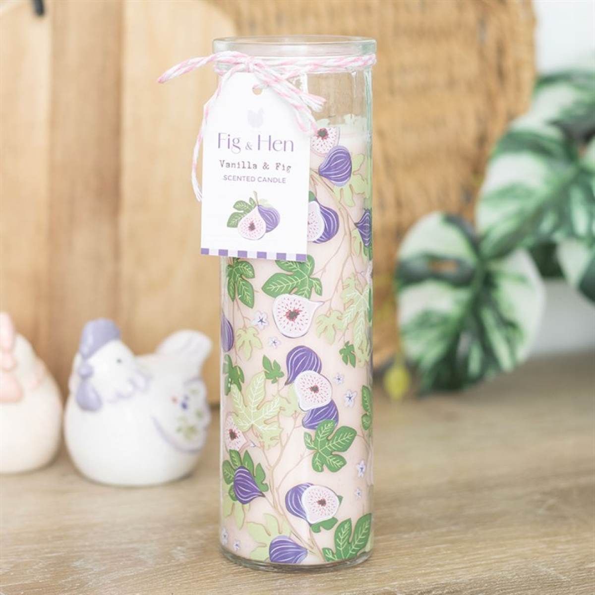 Decorative candle with floral design and vanilla and fig label on a wooden surface.