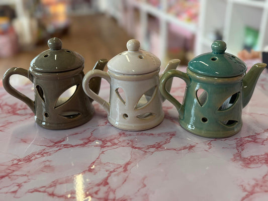 Three ceramic teapots on a marble surface with a blurred background